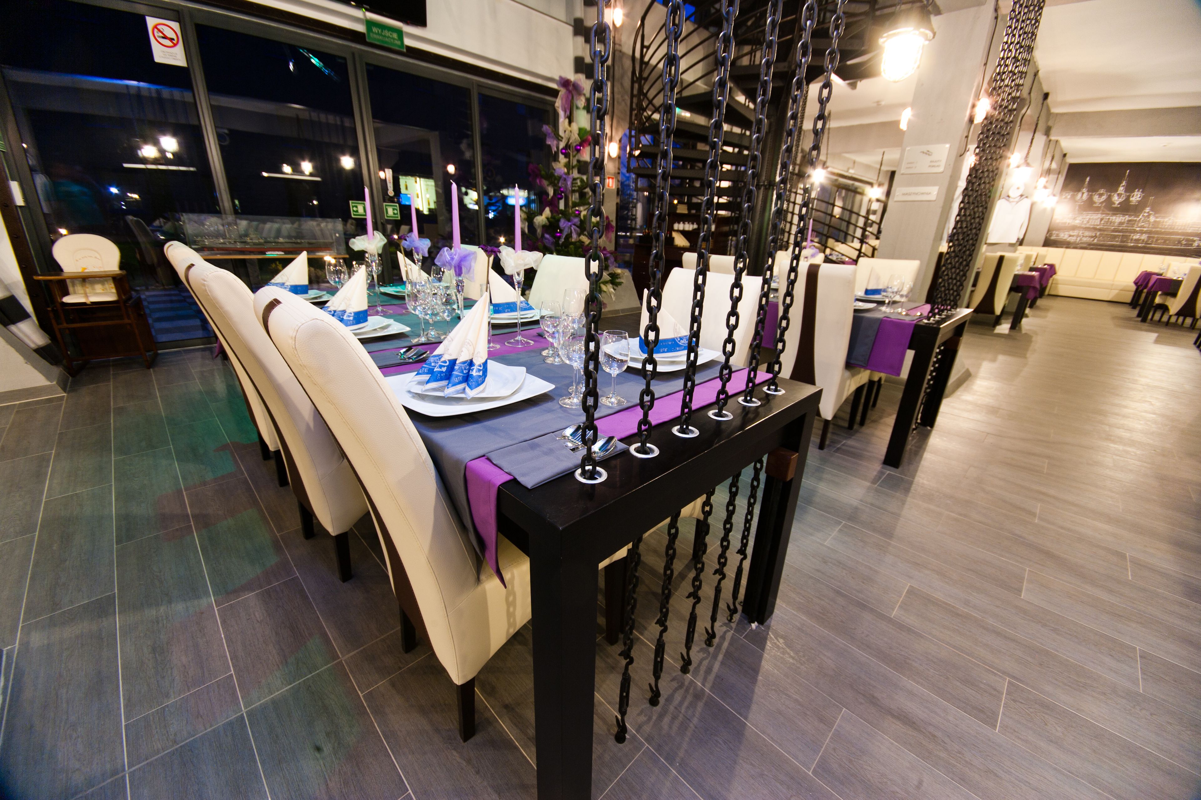 A dining area with a black table, white chairs, and purple tablecloths.