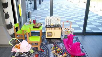 Kids can play and explore in this room's play area, featuring a toy kitchen, stove, and train set.