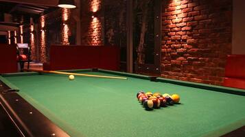 A pool table with balls, a brick wall, and hanging lights.