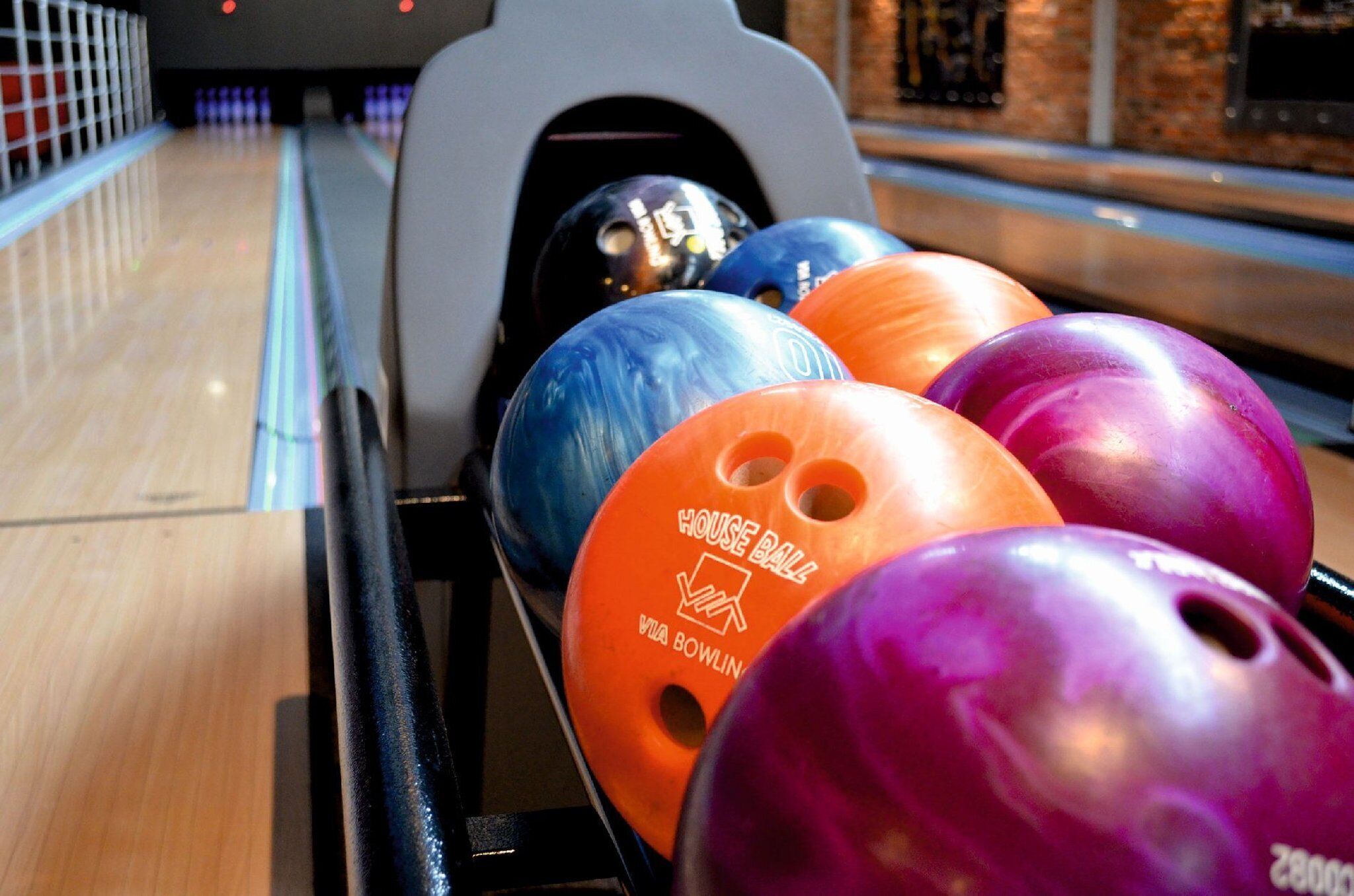 A bowling alley with a lane and several colorful bowling balls.