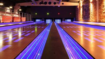 A bowling alley with multiple lanes, wooden floors, and overhead lighting.