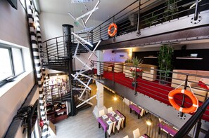 A multi-level hotel lobby with a staircase, seating areas, and a bar.