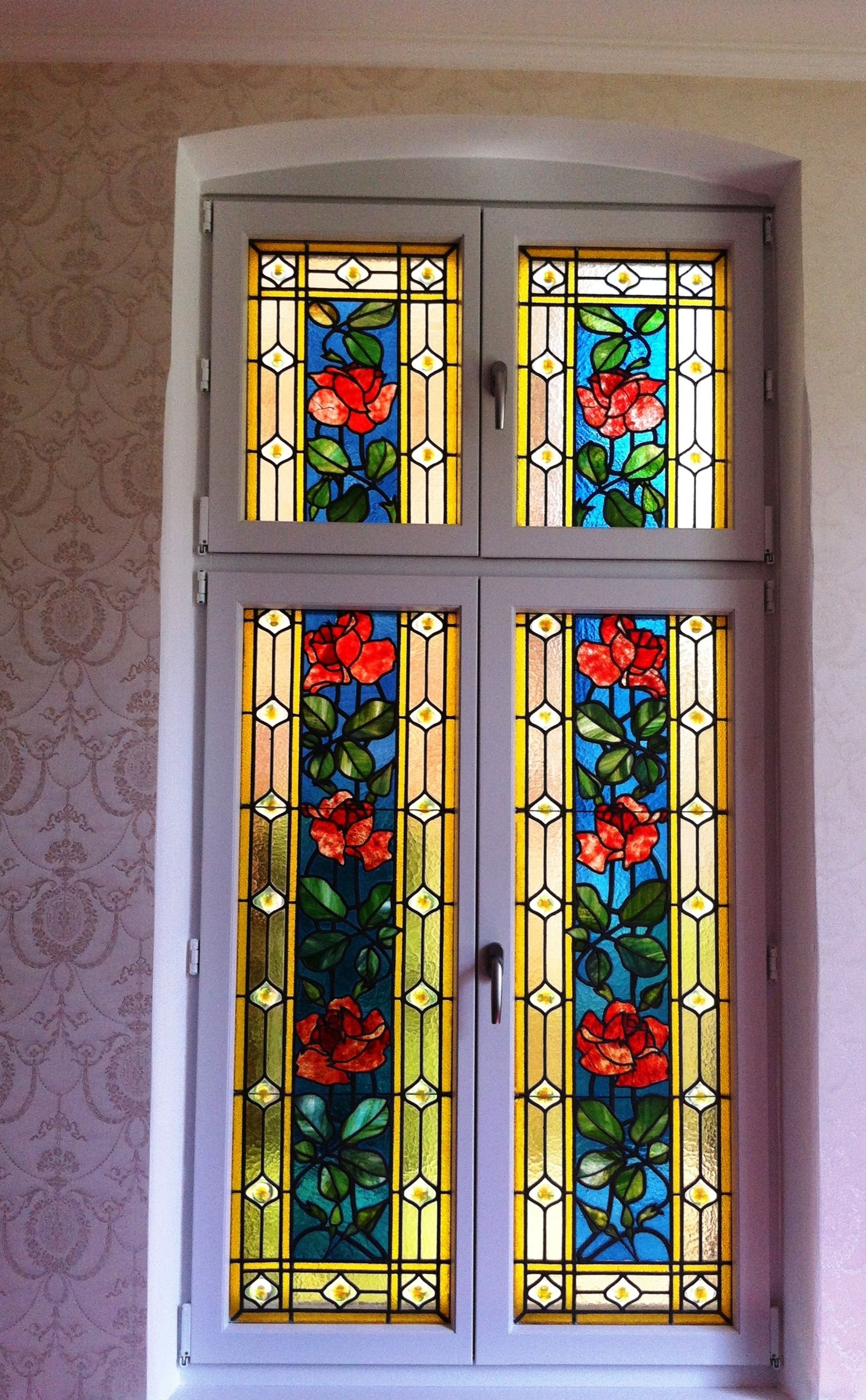 A double door with stained glass windows featuring floral designs.