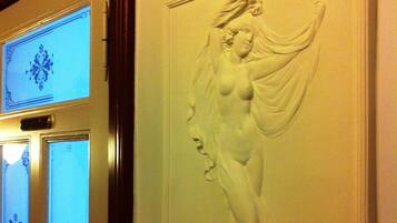 A wall with a relief sculpture of a woman and a door with frosted glass panels.