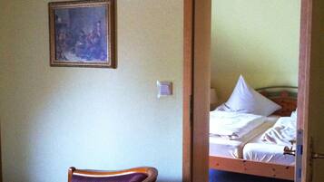 A room with a bed, a chair, a ceiling fan, and a framed picture on the wall.