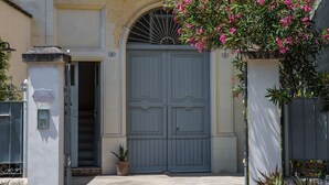 A building with a large arched entrance, a balcony with potted plants, and a gated driveway. - Nuvole Barocche (Lecce)