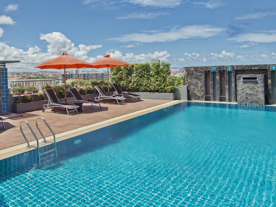 Una piscina al aire libre, sombrillas, sillones reclinables de piscina