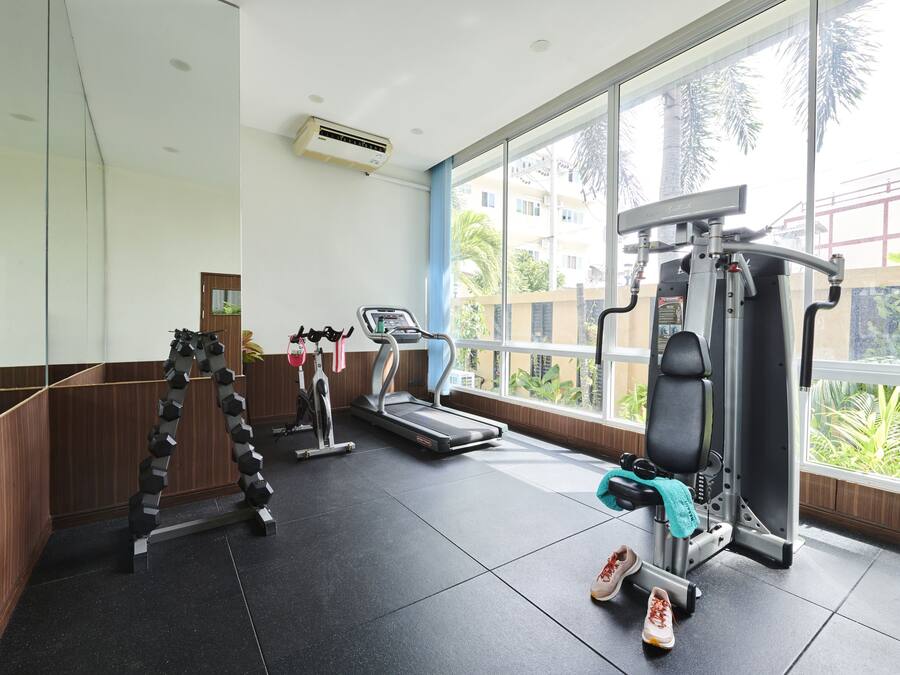A gym with exercise equipment, a treadmill, and a mirrored wall.