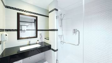 A modern bathroom with a black countertop sink, a large mirror, and a glass-enclosed shower.