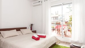A hotel room with a bed, a nightstand, a potted plant, and a view of the outdoor patio area. - The Sky Dome (Barcelona)