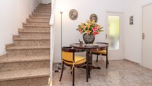 A staircase leading to a dining area with a table and chairs, a vase of flowers, and two framed pictures on the wall. - The Sky Dome (Barcelona)
