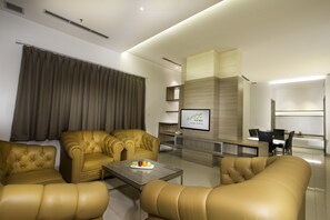 Un salon moderne avec des canapés en cuir, une table basse et un téléviseur à écran plat.