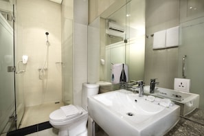 A modern bathroom with a glass-enclosed shower, a large white sink, and a toilet.