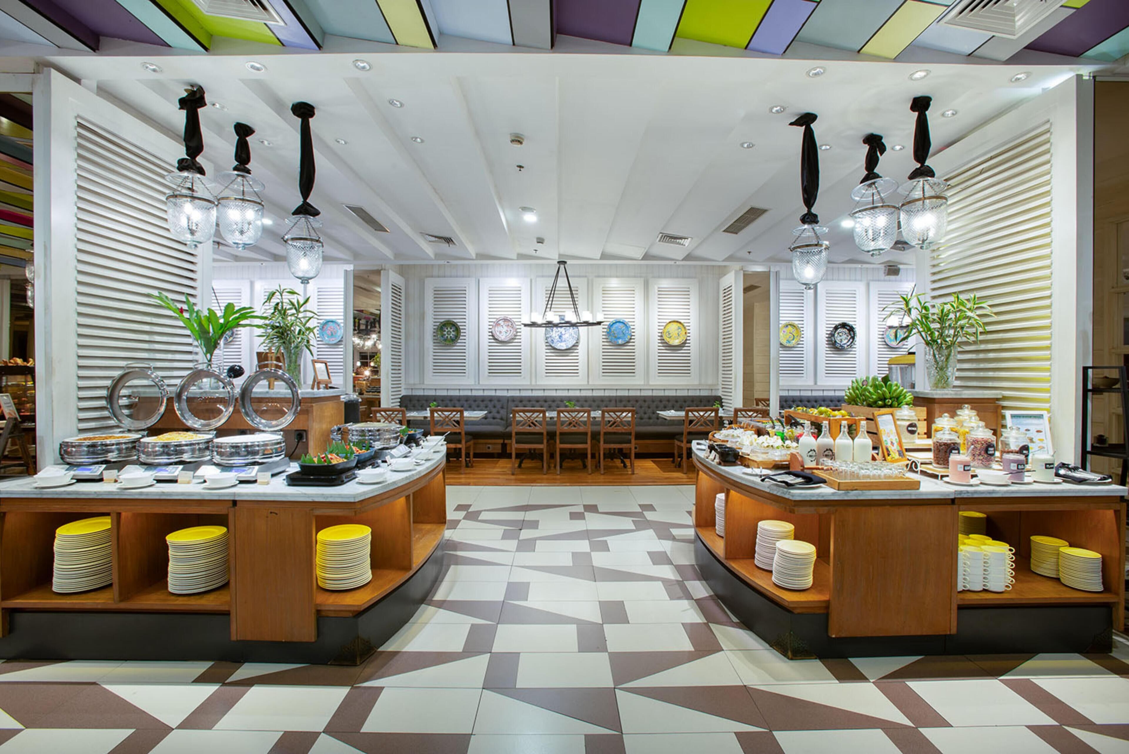 A buffet setup with multiple serving stations, a patterned floor, and a ceiling with colorful panels.