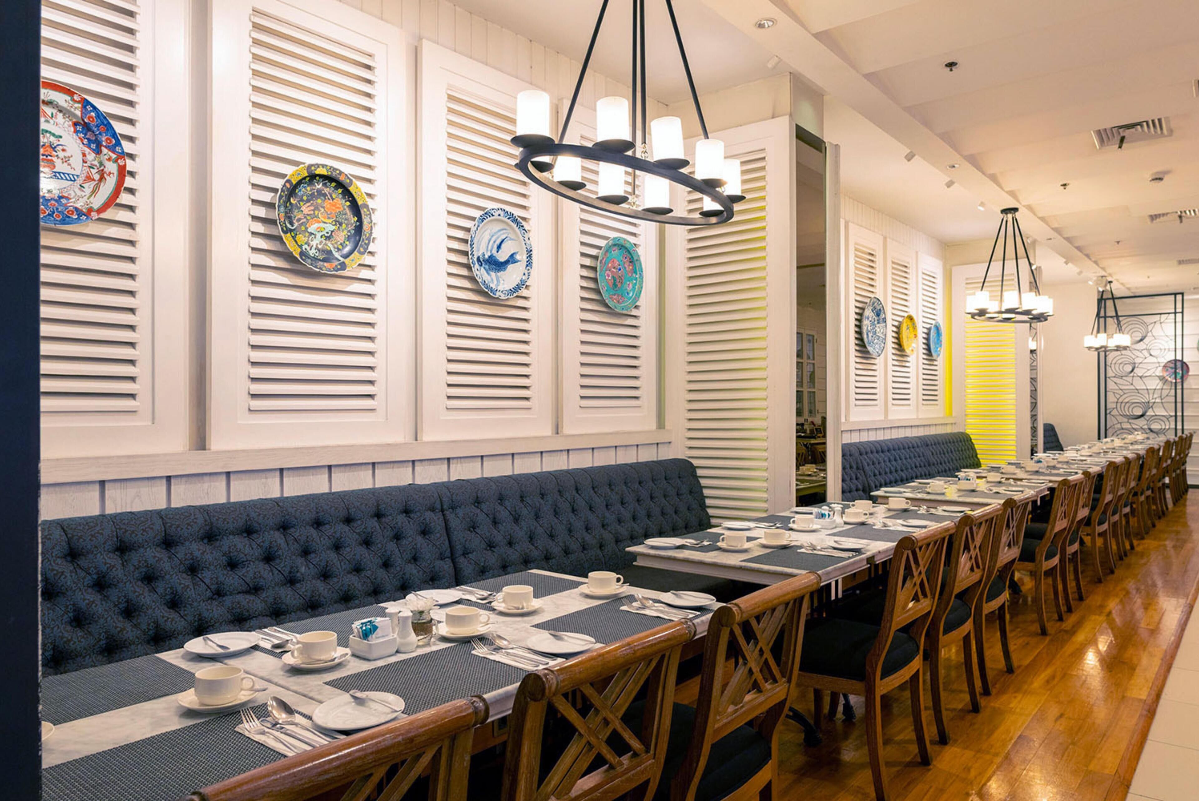 A long dining table with multiple chairs, a blue cushioned bench, and a row of decorative plates on the wall.