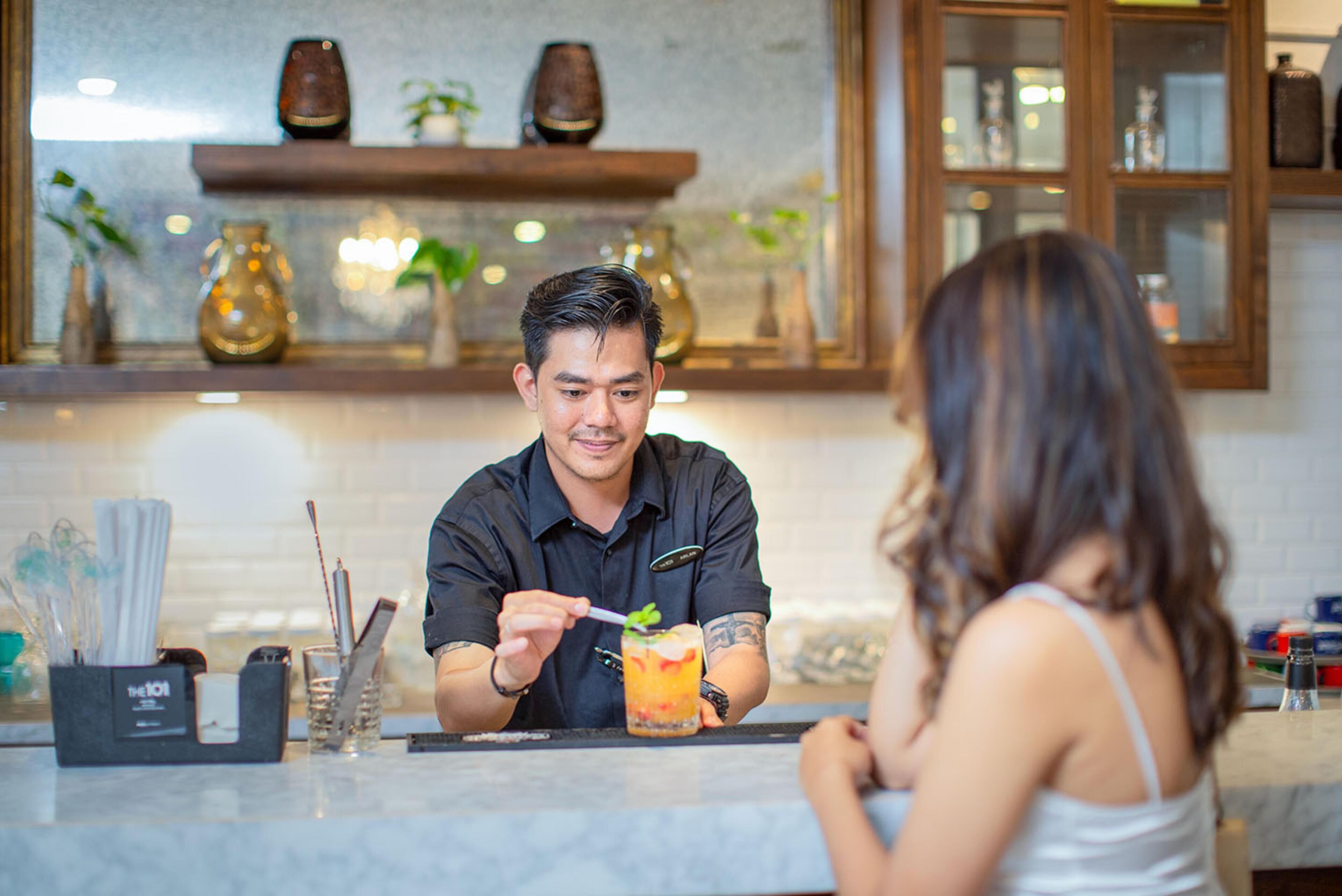 Un espace bar avec un comptoir, une boisson et une personne tenant une cuillère.