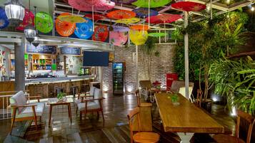 Un restaurante con muebles de madera, sombrillas colgantes y una pared de ladrillo.