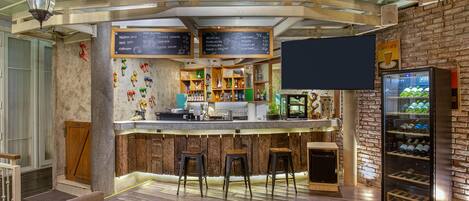 A bar area with wooden stools, a counter with a menu board, and a wine cooler.