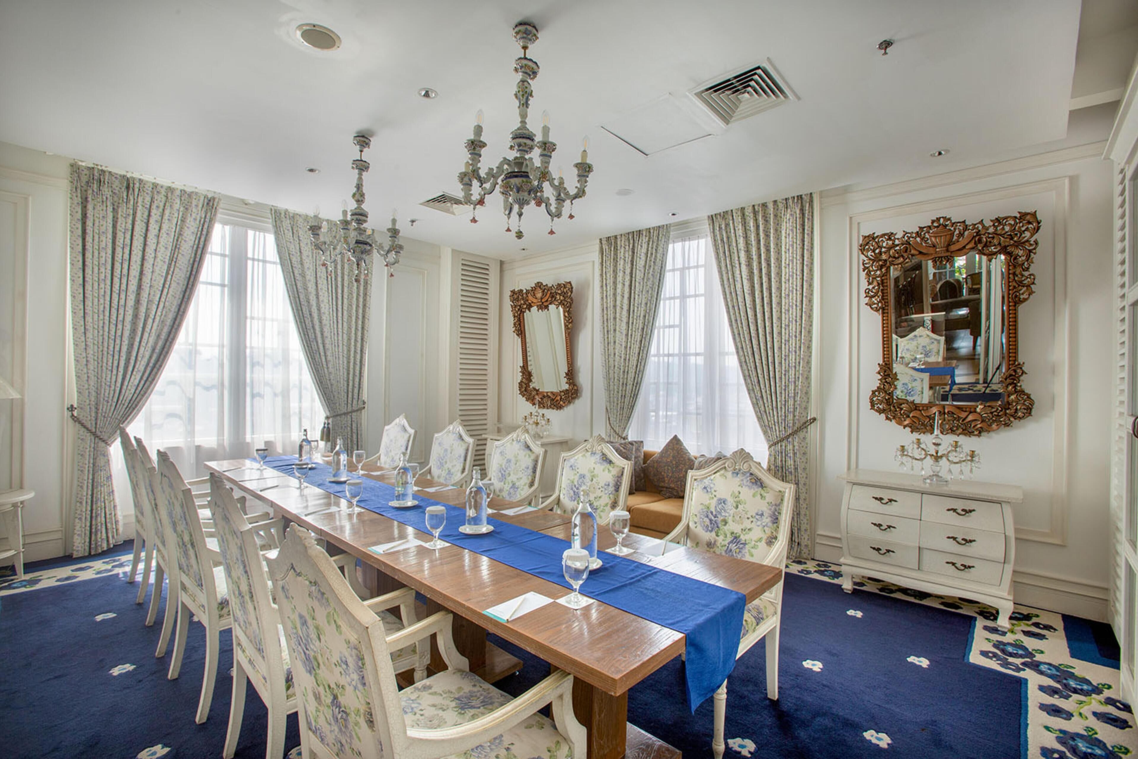 A formal dining room with a long table, chairs, and a chandelier.