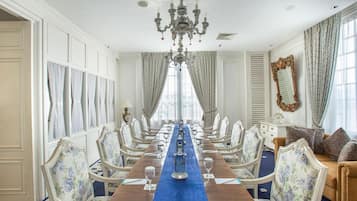 Un comedor formal con una larga mesa, sillas ornamentadas y una araña.