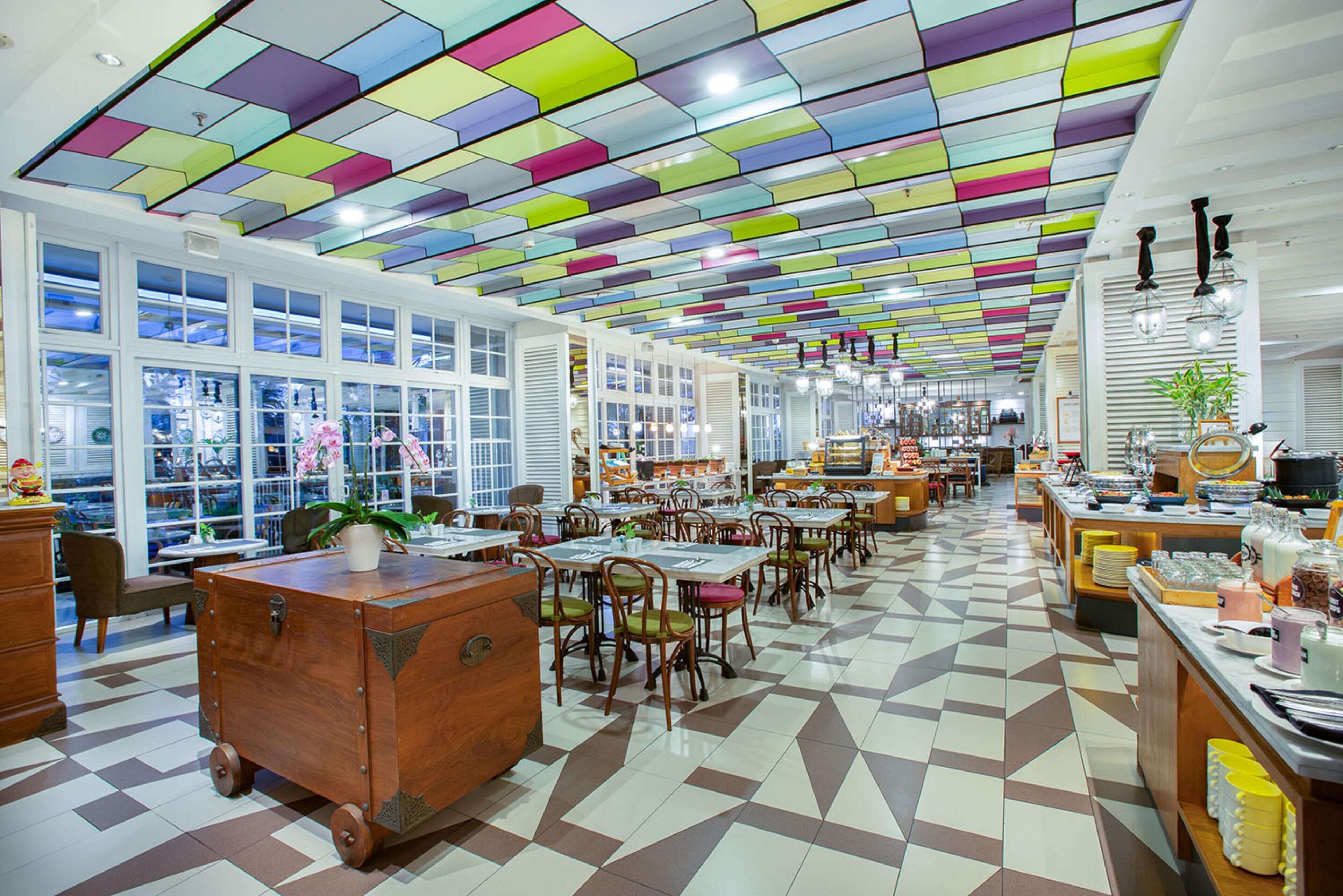 A spacious restaurant with a colorful ceiling, large windows, and a checkered floor.
