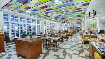 A spacious restaurant with a colorful ceiling, large windows, and a checkered floor.