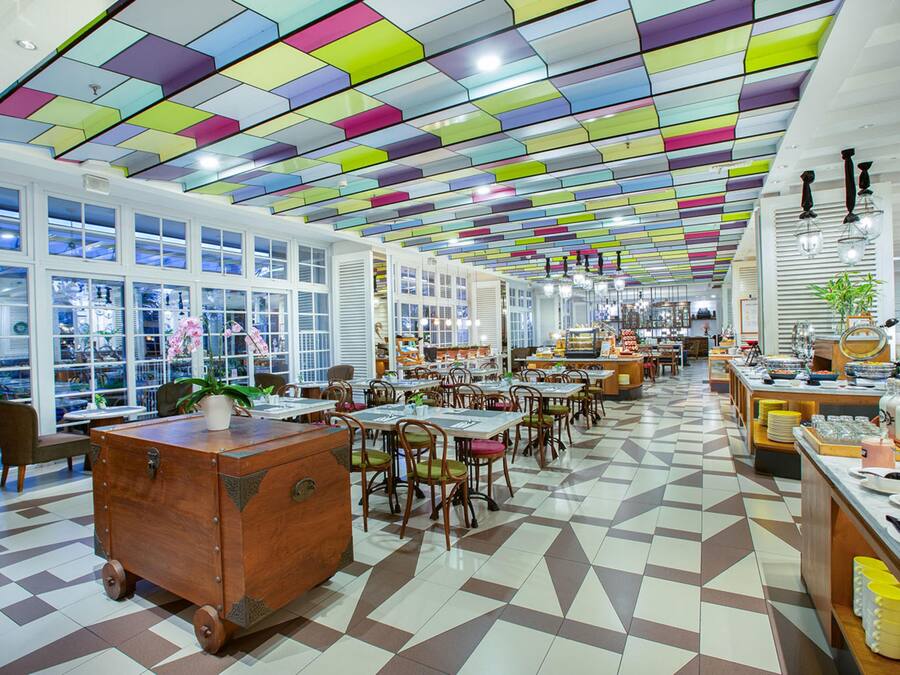 A spacious restaurant with a colorful ceiling, large windows, and a checkered floor.