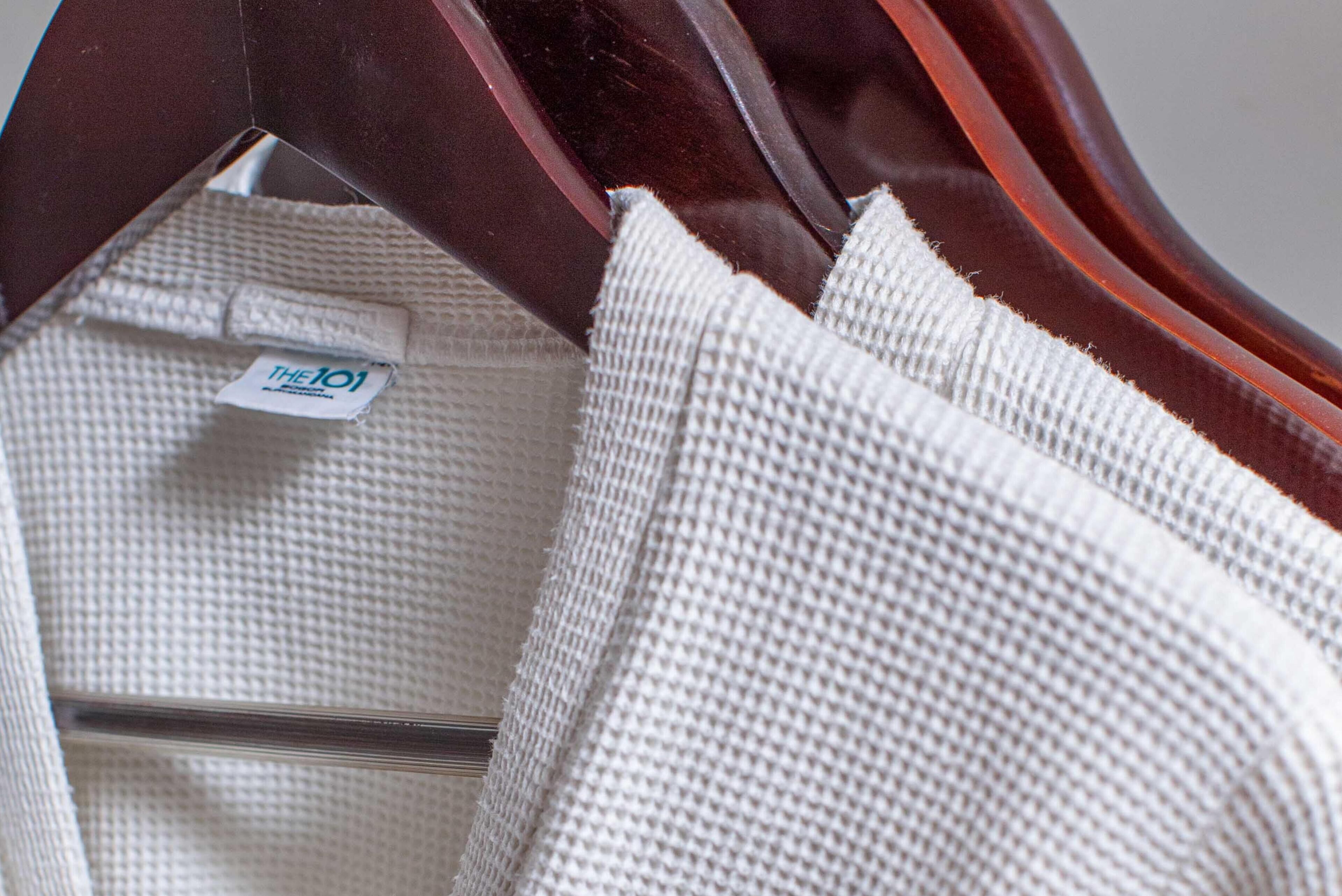 A white towel with a tag reading "THE101" on a wooden hanger.