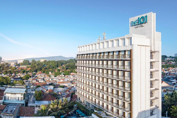 Un hôtel de grande hauteur doté de nombreux balcons, situé dans un quartier urbain densément peuplé, entouré de divers bâtiments et d’espaces verts.