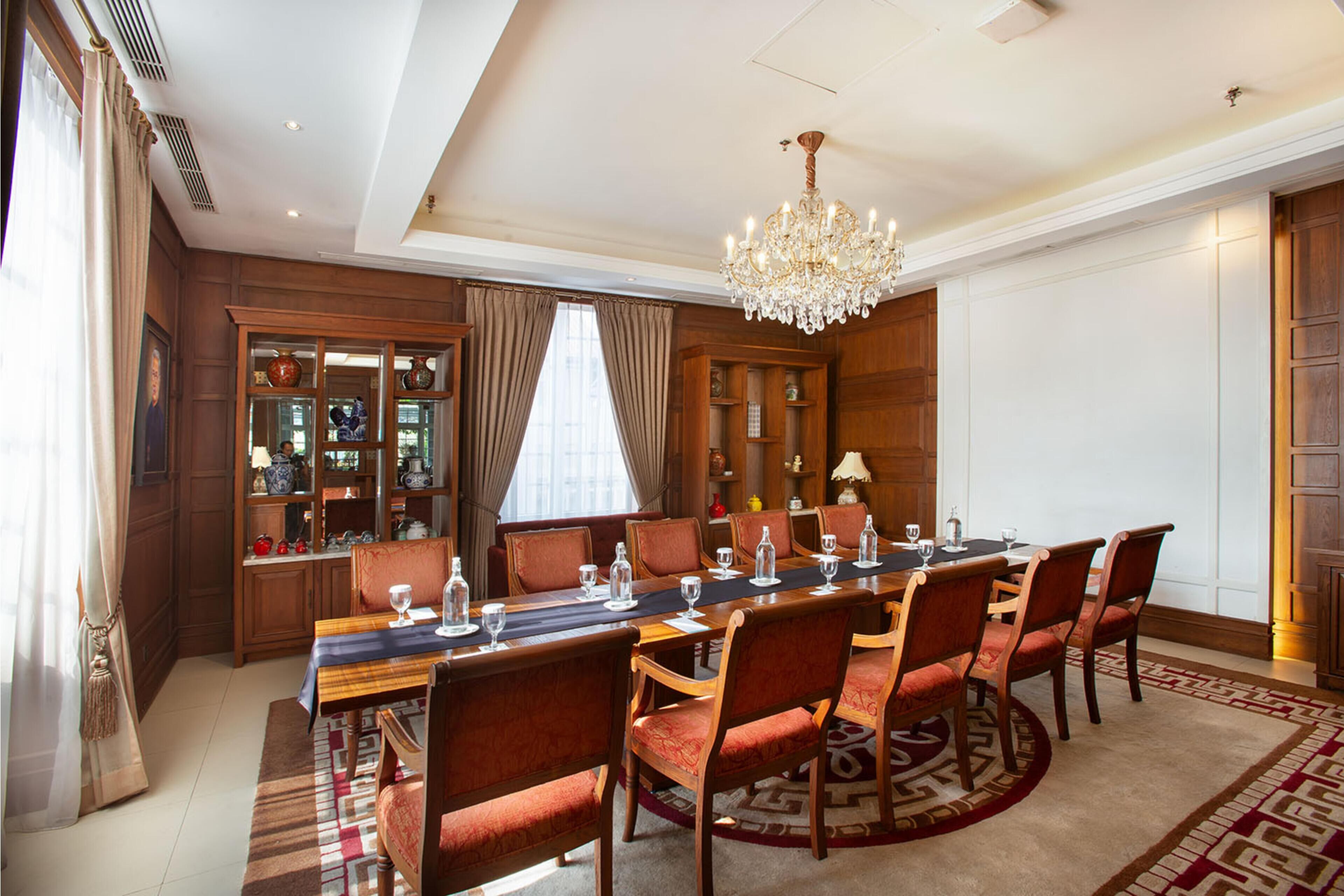 A formal dining room with a long table set for a meal, surrounded by wooden chairs.