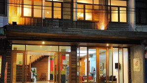 Ein Hotel mit modernem Design, das eine Holzfassade, eine Treppe zu den oberen Stockwerken und eine Rezeption mit Schreibtisch und Stühlen zeigt.