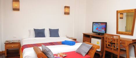 Habitación de hotel con una cama grande, un escritorio con computadora, televisor y espejo.