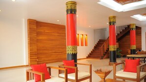 Eine Lobby mit Holzmöbeln, roten und schwarzen Säulen und einer Treppe.