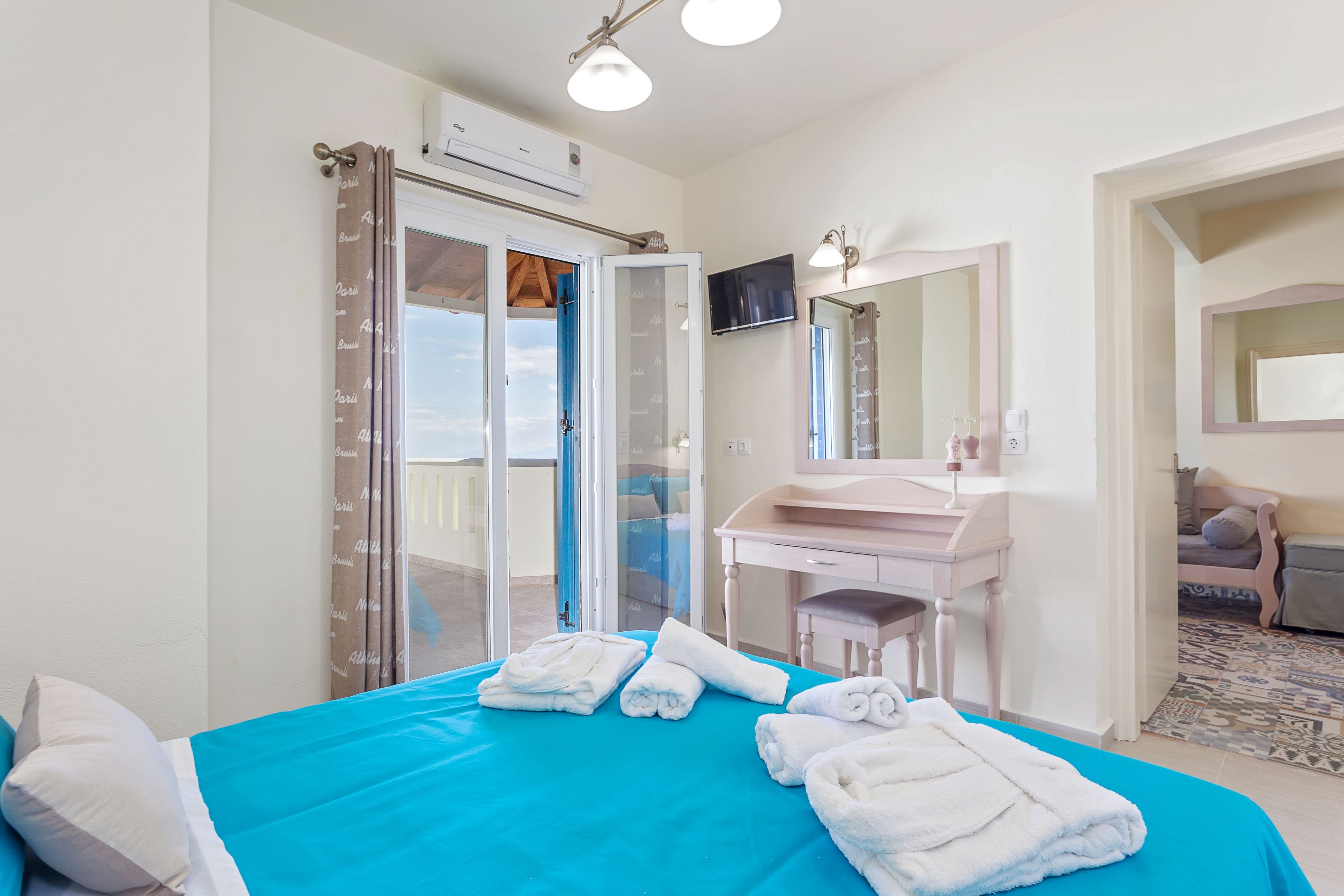A hotel room with a bed, a bathroom with a sink and mirror, and a view through the door.