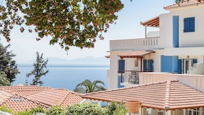 Un bâtiment situé sur la côte, avec un toit recouvert de tuiles en terre cuite, un balcon et une vue sur la mer.