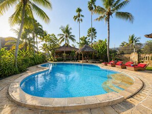 A pool surrounded by palm trees and a gazebo.