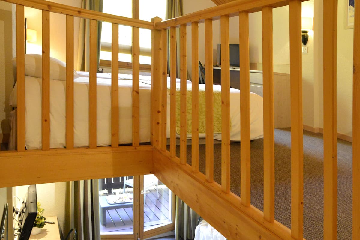 Un escalier en bois mène à une chambre à coucher qui contient un lit et un bureau.