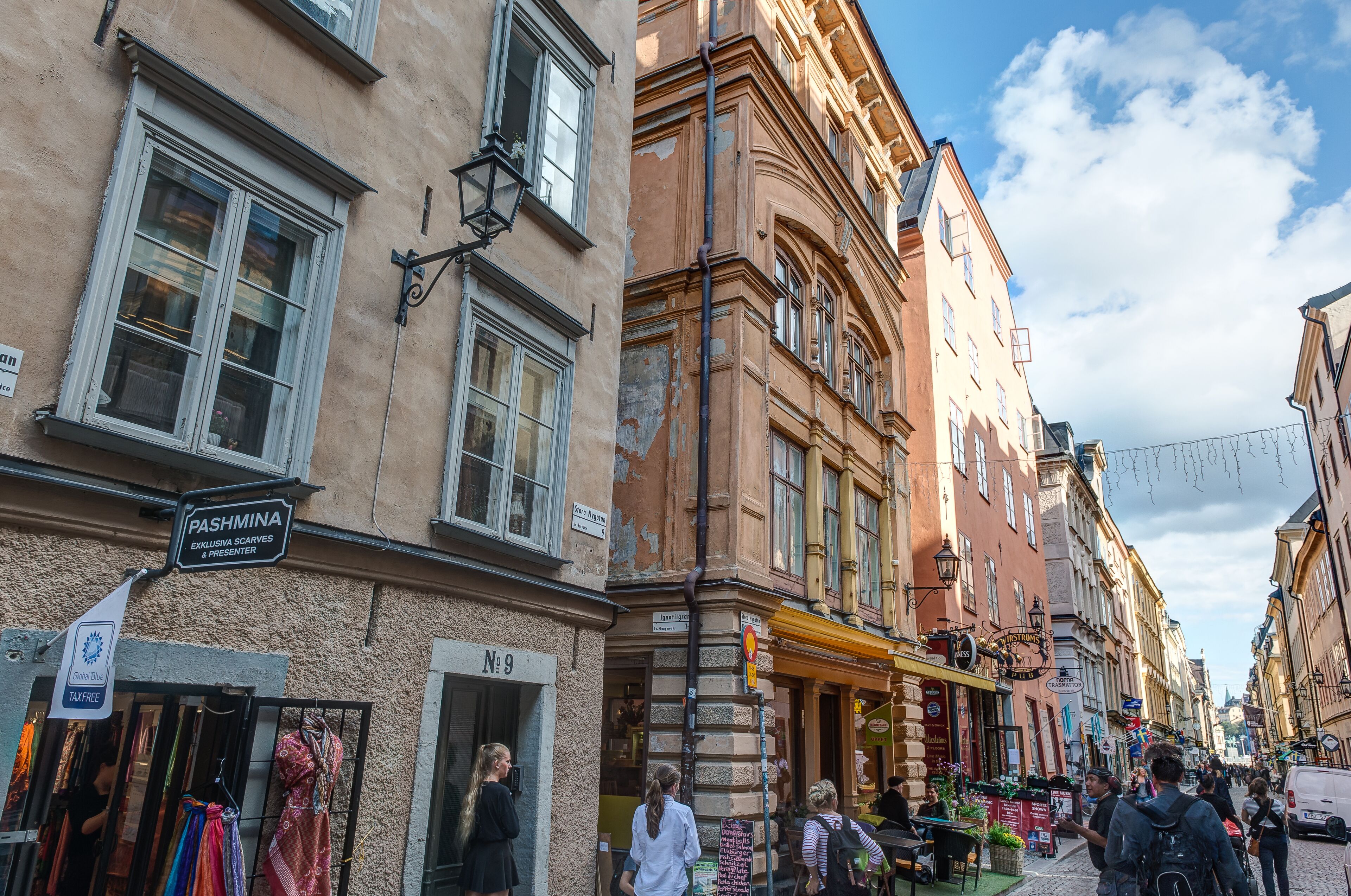 A street with buildings, a sign for 'Pashmina', and a 'No 9' sign.