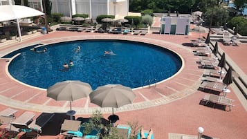 Una piscina al aire libre de temporada, sombrillas