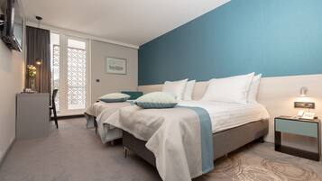 A modern hotel room with a large bed, a desk, and a chair.
