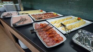 A buffet with various food items including meats, cheeses, and vegetables.