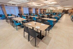Een ruime eetruimte met meerdere tafels en stoelen, gerangschikt in rijen.