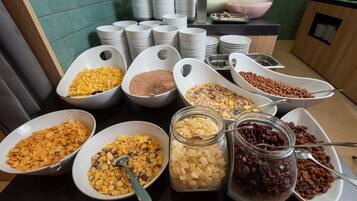 A breakfast buffet with various cereals and toppings in bowls and jars.