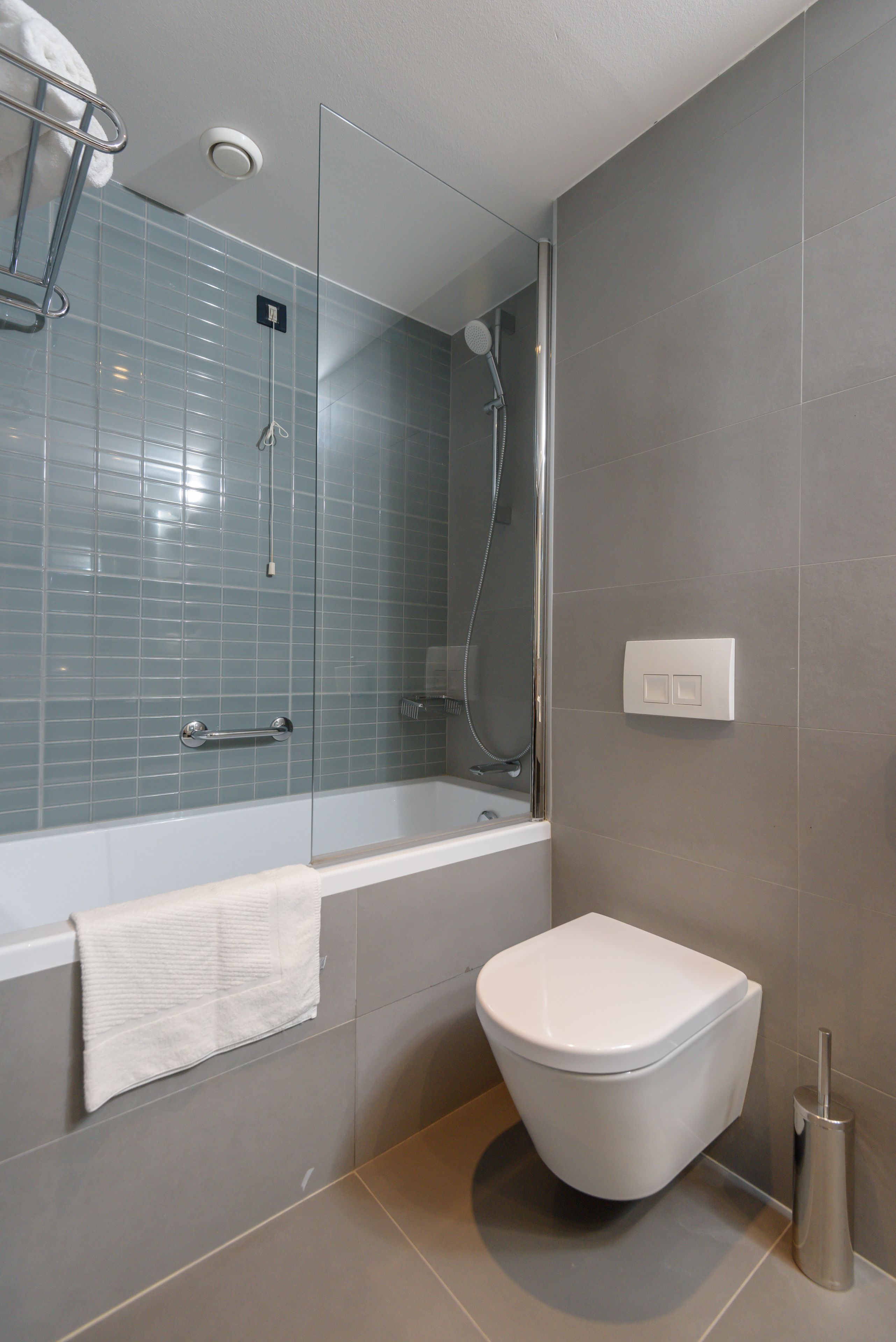 Un baño moderno con ducha de vidrio, una bañera blanca y un inodoro.