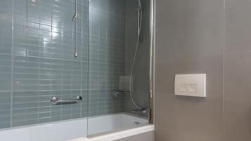 Un baño moderno con ducha de vidrio, una bañera blanca y un inodoro.