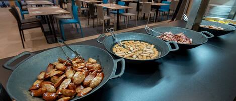 A buffet area with various dishes in pans, including sausages and other meats.