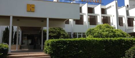 Hotel Kolovare com design moderno, destacando uma entrada imponente e um céu claro.