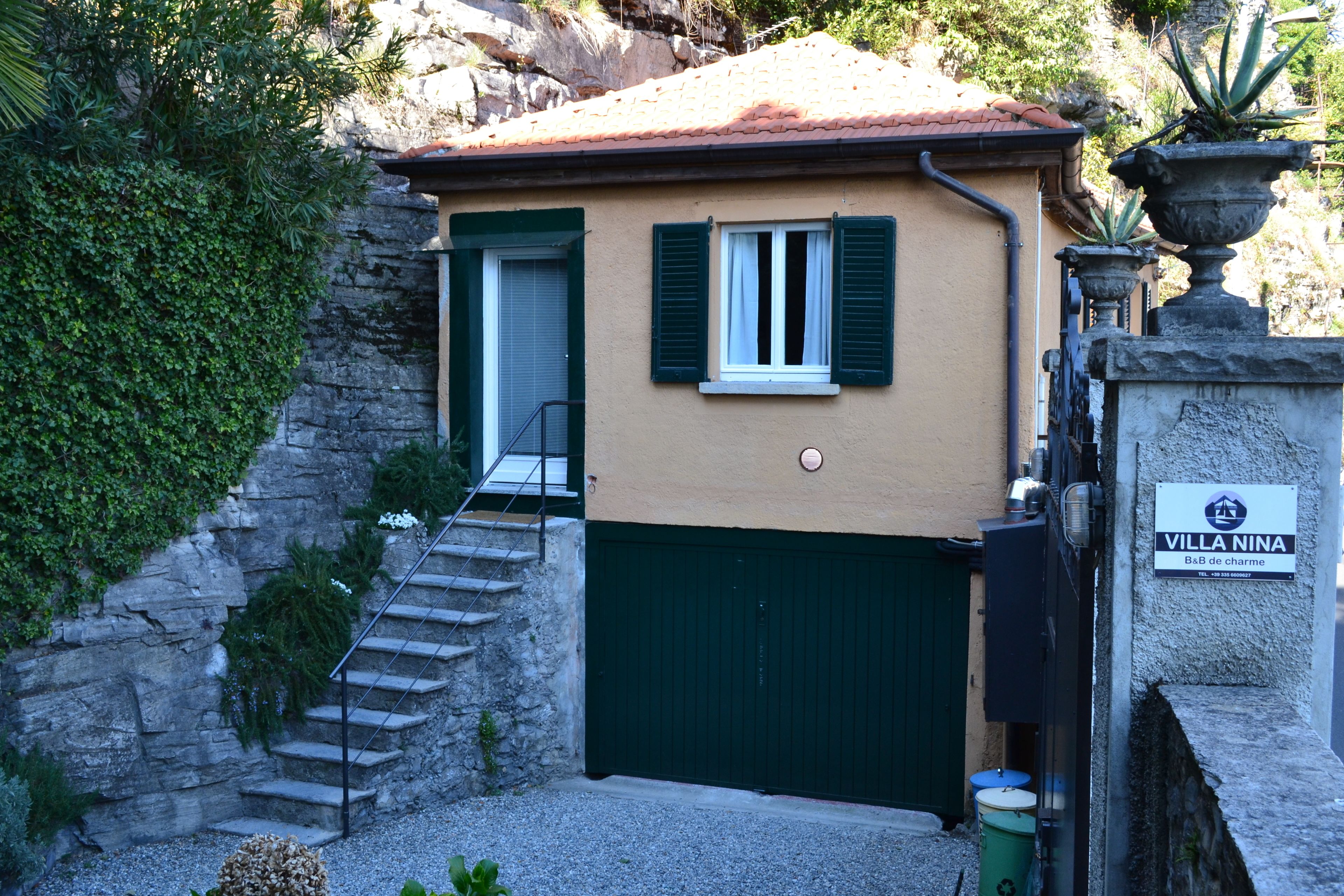 A building with a stone staircase, a green door, and a sign that reads "Villa Nina."
