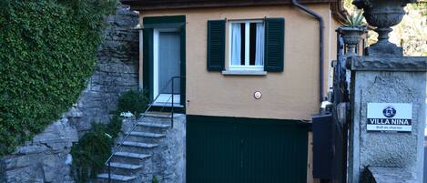A building with a stone staircase, a green door, and a sign that reads "Villa Nina."