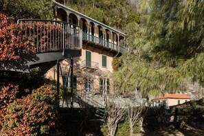 Ein Gebäude mit Balkon, Treppe und Blick auf Bäume und ein Haus.